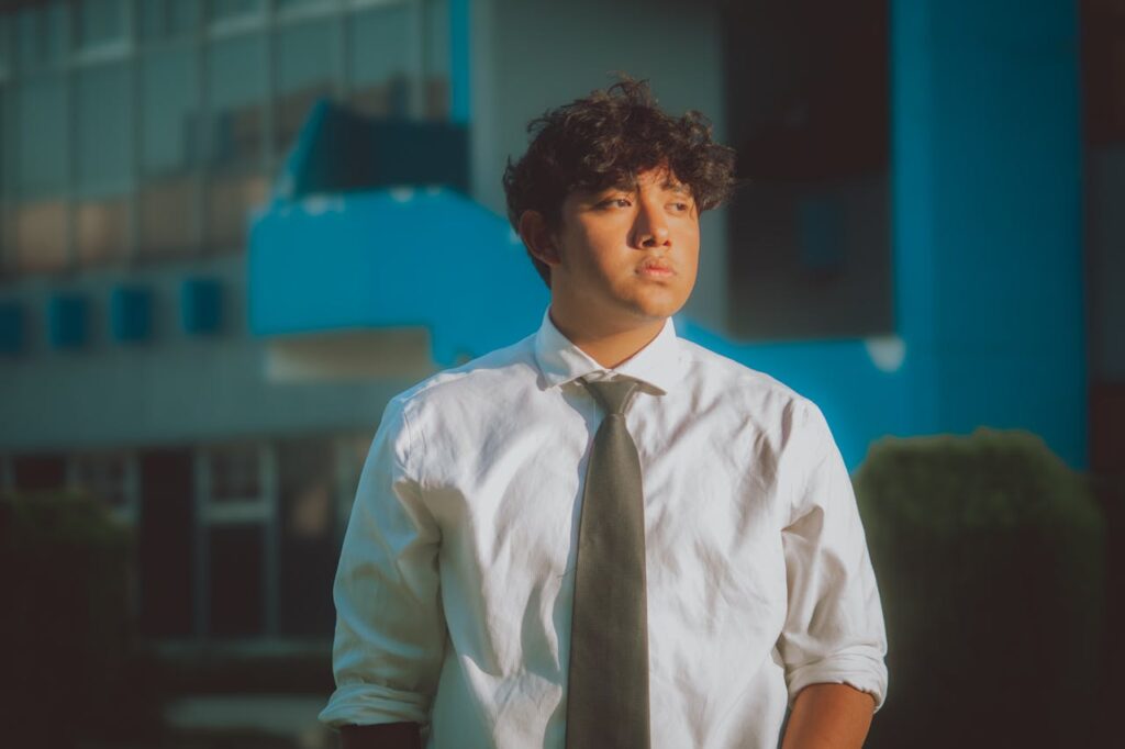A man in a white shirt and tie standing outside